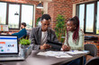 © DC Studio - Businessman explaining marketing strategy on tablet to female coworker in brick wall workspace. African american colleagues sitting at table with documents and having a serious conversation in office.