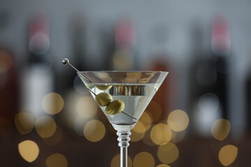 Wall Mural - Martini cocktail with olives in glass on blurred background, closeup. Bokeh effect