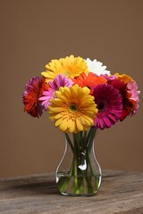 Wall Mural - Bouquet of beautiful gerbera flowers in glass vase on wooden table against brown background