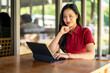 © Wasana - A woman is sitting at a table with a laptop in front of her