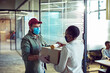 © Marko Geber - Delivery man handing package to office worker in modern workspace