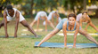 © JackF - Yoga female coach conduct rehearsal for multinational followers in park, leading of performing exercises, do fulfil Prasarita Padottanasana. People practice sport during yoga workout in nature