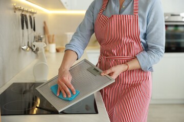 Wall Mural - Woman cleaning filter of kitchen hood with rag indoors, closeup