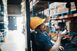 © Davor - Smiling male warehouse worker using smartphone near forklift