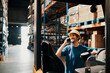 © Davor - Smiling male warehouse worker using smartphone near forklift