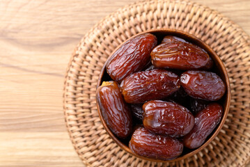 Wall Mural - Date palm fruit (MedJool) in wooden bowl, Table top view