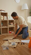 © Krakenimages.com - Young man assembling furniture in a cozy living room surrounded by toys and a shelf, depicting a warm indoor home environment.