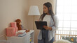 © Krakenimages.com - Woman standing in bedroom with clipboard observing baby room near cradle, showcasing home interior elements with toys and furniture, illustrating a caring atmosphere.