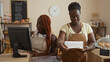 © Krakenimages.com - African american black women bakers working in a bakery, one operating a cash register while the other rings up an order in an indoor shop setting.