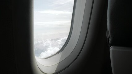 Wall Mural -  through the window of the airplane from inside cabin while flyiing climbing into the sky above the cloudscape outside in summer day,natural transportation holiday vacation background