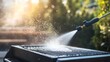 © ธนากร บัวพรหม - A person cleaning a barbecue grill with a pressure washer, showcasing the sunlight and droplets of water in the background.