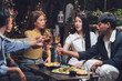 © Kritdanai - Nighttime Cheers: Friends raise a toast, celebrating life's moments with laughter and shared drinks at an outdoor evening gathering. The warm lighting enhances the convivial atmosphere.