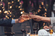 © Kritdanai - Whiskey Toast: Two hands elegantly clinking glasses of amber whiskey against a softly blurred background of warm lighting and celebratory atmosphere. A sophisticated image representing success.