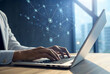© Butsarakham - A person types on a laptop, with digital network connections appearing above, symbolizing technology and connectivity in a modern workspace.