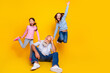 © deagreez - Happy family with a grandfather and his granddaughters enjoying fun time together in front of a yellow background.