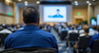 © Easy - A man in his fifties listens attentively from the audience as a speaker presents on stage during a business conference event