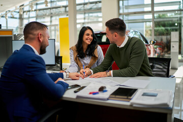 business professionals engaging in a discussion around a car purchase agreement at a dealership. smi