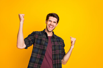 Wall Mural - Photo of amazing guy worried about football game raising fists supporting team wear casual plaid shirt isolated yellow color background