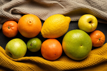 Wall Mural - A bunch of fruit including oranges, lemons, and apples are displayed on a table. The oranges are on the left, the lemons are in the middle, and the apples are on the right