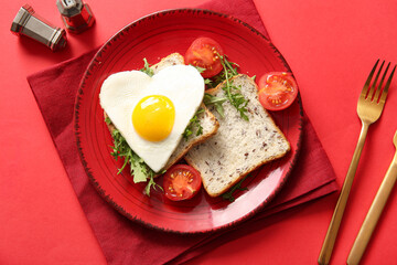 Plate with tasty fried egg, toasts, tomatoes and arugula on red background