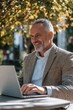 © vefimov - Happy businessman with a beard working on a laptop in the sunlight.
