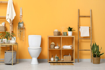 Wall Mural - Interior of stylish restroom with white toilet bowl, coffee table and shelving unit near orange wall