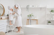 © Pixel-Shot - Cute little happy girl and her mother in bathrobes applying cream at home