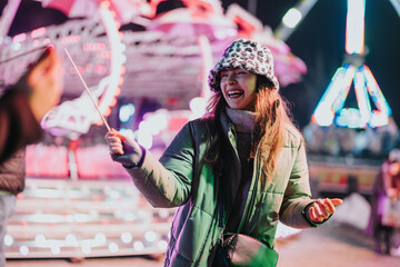 Poster - Cheerful woman enjoying a festive evening at a vibrant winter fair with bright lights.