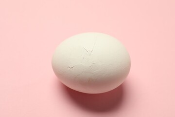 Wall Mural - One egg with cracked shell on pink background, closeup