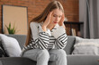 © Pixel-Shot - Worried young woman sitting on sofa at home