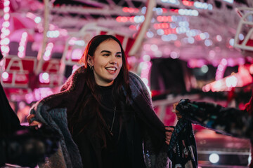 Poster - A woman smiles warmly while enjoying the vibrancy of a decorated winter carnival at night.