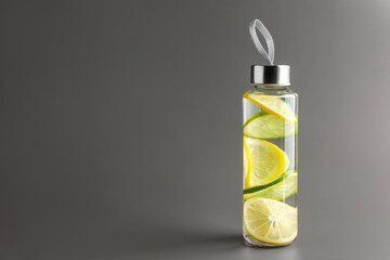 Wall Mural - Lemon water with lime in bottle on light grey background, space for text