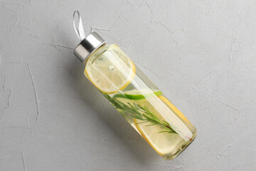 Wall Mural - Lemon water with lime and rosemary in bottle on grey table, top view