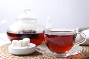 Wall Mural - Refreshing black tea in cup and sugar on light table