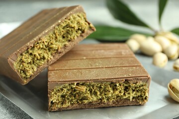 Wall Mural - Pieces of tasty Dubai chocolate with pistachios and knafeh on grey textured table, closeup