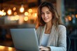 © Mariya - Smiling professional woman entrepreneur in office working on laptop at desk with warm light focused on project