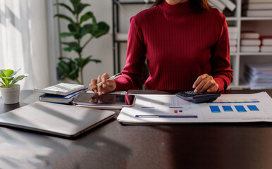 Wall Mural - Business financing accounting banking concept. Business woman hand doing finances and calculate on desk about cost at home office. Woman working on desk with using calculator, finance accounting.
