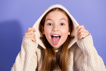 portrait of a joyful young girl in a beige sweater posing against a vibrant purple backdrop