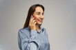 © muse studio - Smiling woman wearing a blue shirt talking on a smartphone with a friendly expression indoors