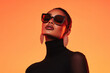© Papukos - Fashion model posing with sunglasses and earrings on orange background