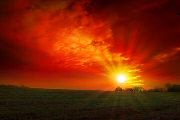 Wall Mural - Red sunset background with sun and big abstract clouds.
