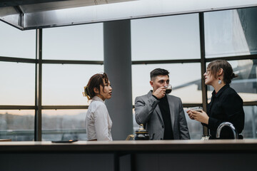 Wall Mural - A group of business professionals are interacting in a contemporary office environment, discussing work over coffee. They exhibit professionalism and teamwork in a modern workplace setting.