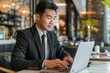 © darshika - A businessman in a suit works on his laptop in a modern cafe, focused on his task.