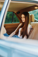 Wall Mural - Thoughtful young woman with long hair sitting in a car, reflecting on life, capturing emotions in a serene setting.