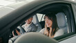 © ihorvsn - Side camera view of positive woman exclaiming with joy while sitting at driver seat in new car. Husband smiling while sitting besides her. Shopping for new vehicle. Positive emotions.