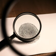© Miguel - A magnifying glass focuses on a detailed fingerprint, showcasing the intricacies of forensic analysis and investigation on paper. Ideal for themes of identity, security, and research.