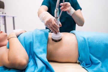 Wall Mural - Professional dermatologist performing radio frequency lifting procedure on the stomach of a woman. Female client getting rf-lifting treatment on her belly at cosmetology clinic