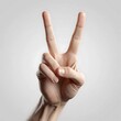 © Penggila - Hand Showing Peace Sign Gesture Against Soft Gray Background Image