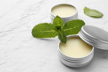 Sticker - Mint lip balms and green leaves on beige textured table, closeup. Space for text