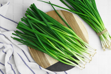 Wall Mural - Fresh green onions on white tiled table, top view